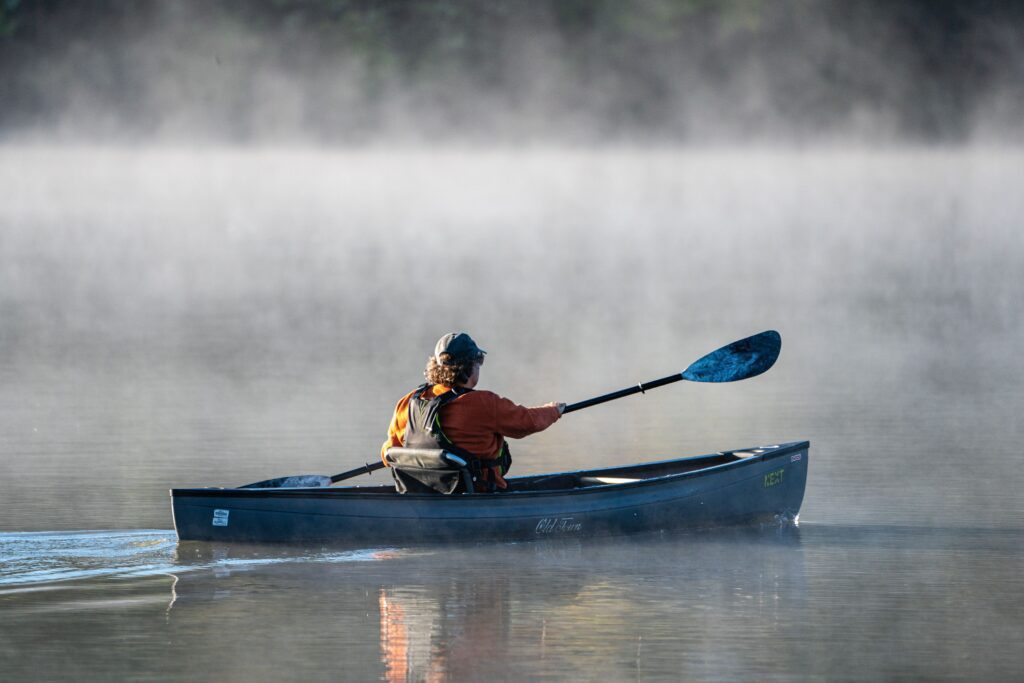 Solo person in a canoe on a fog shrouded lake