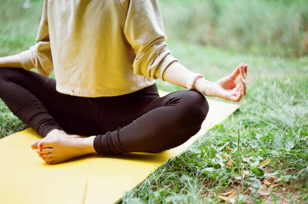 Woman doing yoga on a mat sitting on the grass